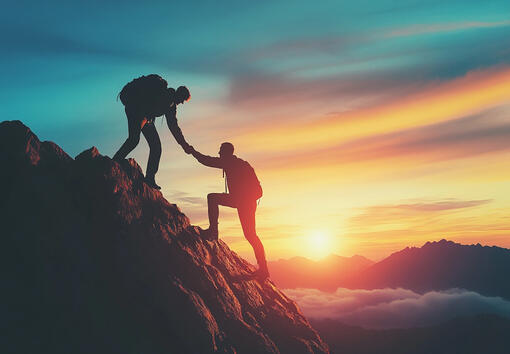 Climber helping another ascend a mountain, representing guidance and support